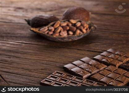 Dark homemade chocolate bars and cocoa pod on wooden . Milk and dark chocolate on a wooden table