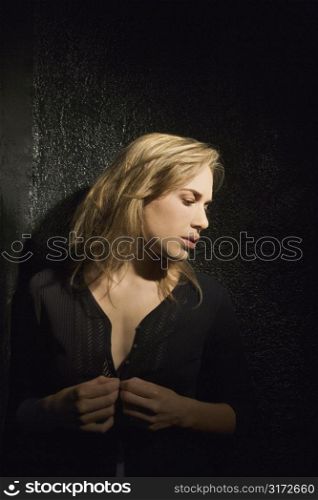 Dark portrait of sexy Caucasian mid-adult woman looking to side.