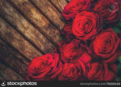 dark red fresh roses laying on wooden table, toned. dark red roses on table