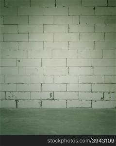 Dark room with cement floor and block wall background. Vintage filter effect