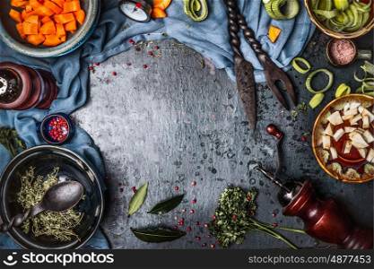 Dark rustic vegetarian food background with bowls of chopped vegetables and seasoning ingredients and kitchen tools, top view, frame. Vegan or vegetarian nutrition, diet and healthy food concept