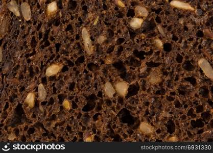 Dark rye bread with sunflower seeds closeup for background