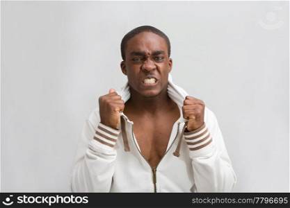 Dark skinned handsome young man, grabs his stylish white hooded shirt; Very angry! Isolated