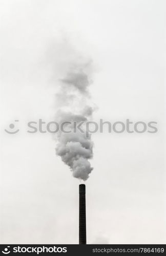 Dark smoke stack billowing smoke into air on overcast sky.