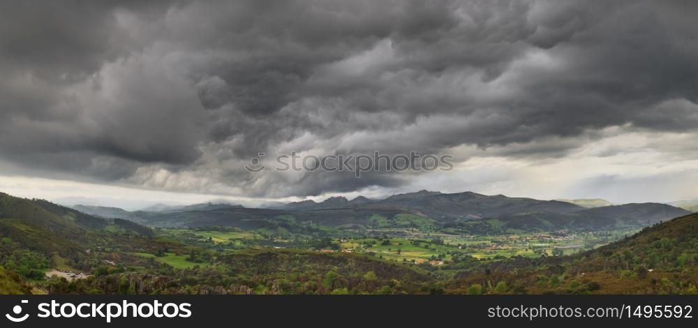 Dark stormy clouds over a green valley in Cantabria Spain