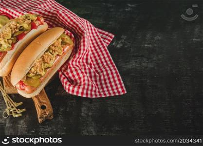 dark surface with tablecloth two delicious hot dogs