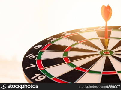 Dart arrow hit to center on bullseye bull’s-eye  of a dartboard is a target of purpose challenge business at sunset, expert strategy market target, objective financial and goal a concept