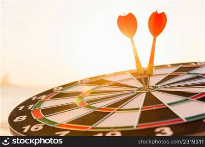 Dart arrow hitting to center on bullseye (bull&rsquo;s-eye) dartboard is the target of purpose challenge business at sunset, expert marketing strategy target, objective financial and goal success