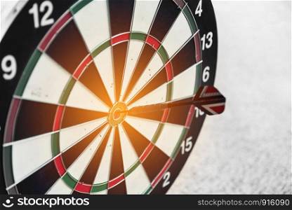 Dart board and arrow in middle. Business and success concept. Achievement and target theme. Orange sun light effect. High contrast tone