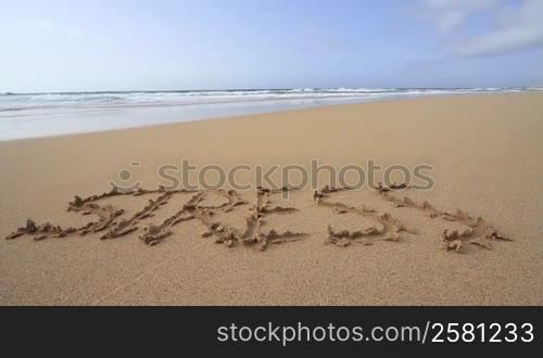 "Das Wort "Stress" am Sandstrand in den Sand geschrieben"