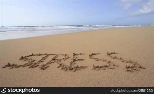 "Das Wort "Stress" am Sandstrand in den Sand geschrieben"