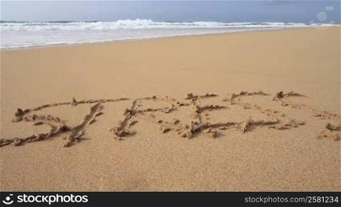"Das Wort "Stress" am Sandstrand in den Sand geschrieben."