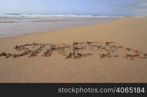"Das Wort "Stress" am Sandstrand in den Sand geschrieben."