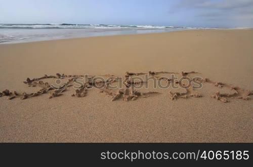 "Das Wort "Stress" am Sandstrand in den Sand geschrieben. Es wird vom Meerwasser weggespuhlt."