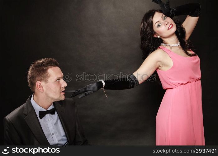 Date. Gallant man in suit and woman in evening dress on black grey background in studio.