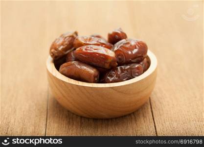 date palm dried fruit in wooden bowl on wood background