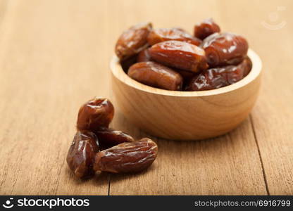 date palm dried fruit in wooden bowl on wood background