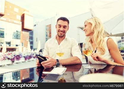 date, people, payment and finances concept - happy couple with wallet and wine glasses paying bill at restaurant