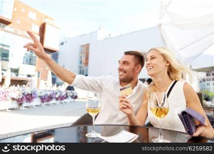 date, people, payment and finances concept - happy couple with wallet, credit card and wine glasses calling waiter for bill payment at restaurant