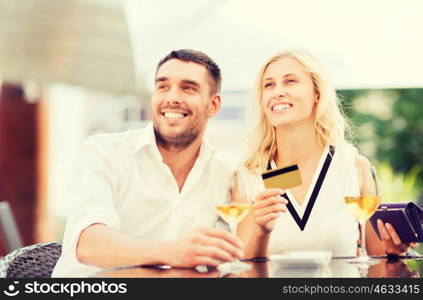 date, people, payment and relations concept - happy couple with credit card, bill and wine glasses at restaurant terrace