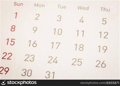 Dates of calendar pages, weekly start from sunday with red color. Closeup shown dot prints, blurred at the edges, vintage minimal style background. Time management, schedule, appointment reminder.