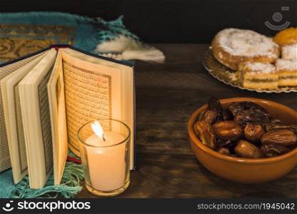 dates pastry near burning candle opened book. High resolution photo. dates pastry near burning candle opened book. High quality photo