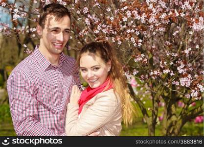 Dating. Young woman and man walking, couple in love relaxing in blossoming cherry trees park at sunny spring day
