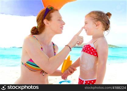 daughter and mother in beach with sunscreen in bikini