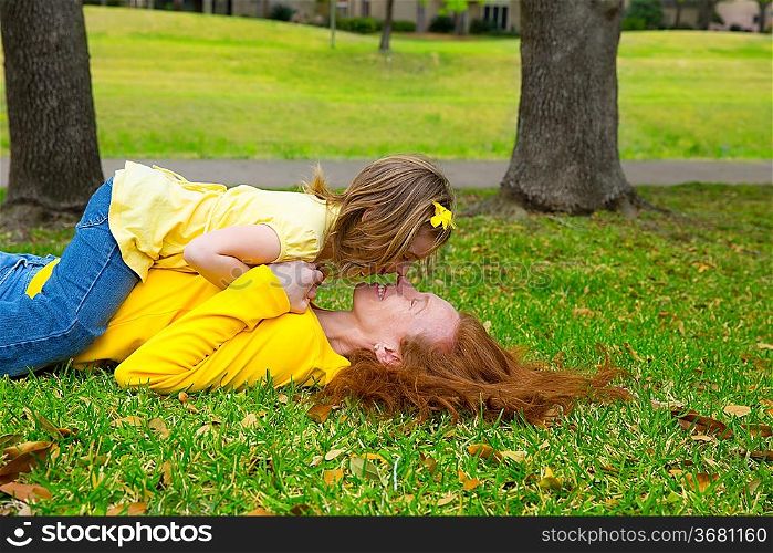 Daughter and mother nose kissing lying on park lawn outdoor