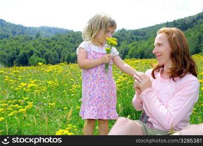 Daughter and mother playing in spring flowers meadow outdoor
