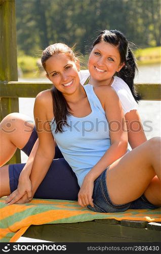 Daughter and mother sitting on pier relaxing smiling teen comfortable