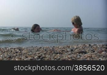 daughter and mum lay joyful in sea water.