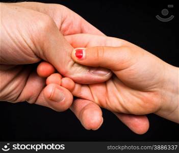 Daughter connecting with fathers hand isolated towards black
