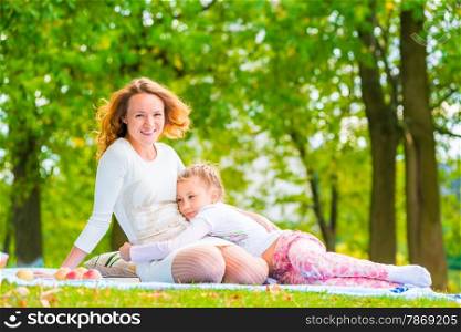 daughter embracing her mother lying on the lawn