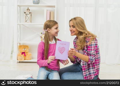 daughter giving greeting card mother