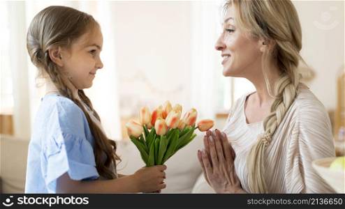 daughter giving mother bouquet tulips as gift