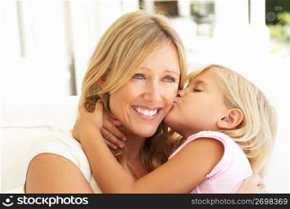 Daughter Giving Mother Kiss Relaxing On Sofa