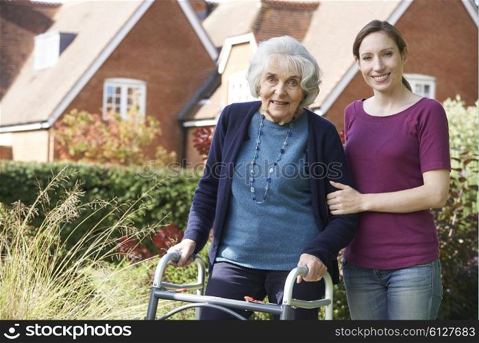 Daughter Helping Senior Mother To Use Walking Frame