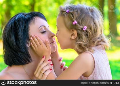 Daughter holds the face of his mother and kisses closeup
