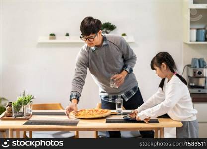 Daughter little girl help dad to setting up dining table before meal. Asian happy family doing domestic life together.