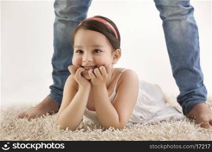 Daughter lying between father's legs on rug