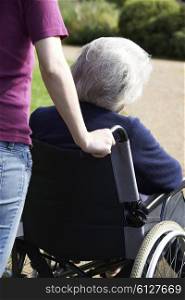 Daughter Pushing Senior Mother In Wheelchair