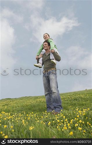 Daughter sits on father&acute;s shoulders