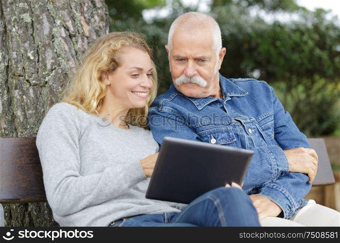 daughter with her father using tablet in the park