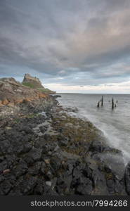 Dawn breaks over Lindisfarne Castle on Holy Island Northumberland with the stars and Milky Way still overhead in the fading night sky.