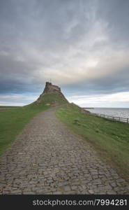 Dawn breaks over Lindisfarne Castle on Holy Island Northumberland with the stars and Milky Way still overhead in the fading night sky.