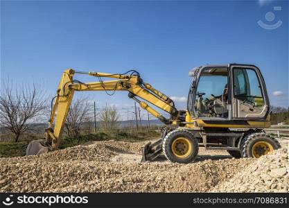 day view of yellow excavator with a shovel in action at the construction site