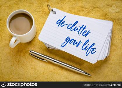de-clutter your life - handwriting on a stack of index cards with a cup of coffee and a pen against yellow textured paper