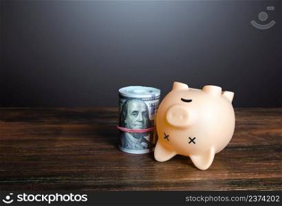 Dead pig piggy bank with money. Financial crisis, depletion of savings and bankruptcy. Default, non-payment of obligations. Devaluation, inflation. Impoverishment. Refinancing restructuring of debts