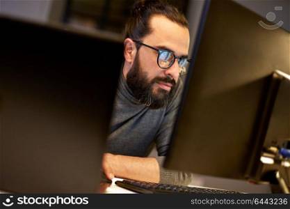 deadline, technology and people concept - close up of creative man in glasses working at night office and thinking. close up of creative man working at night office
